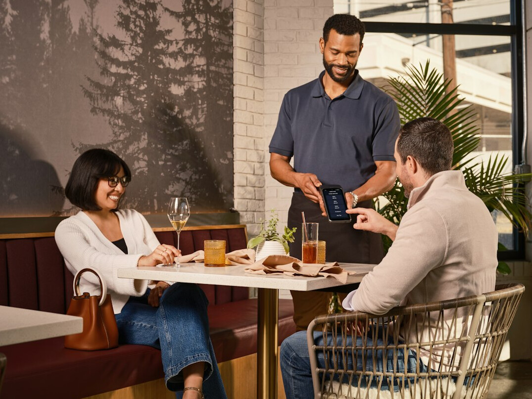 Team of colleagues collaborating around a wooden table with laptops